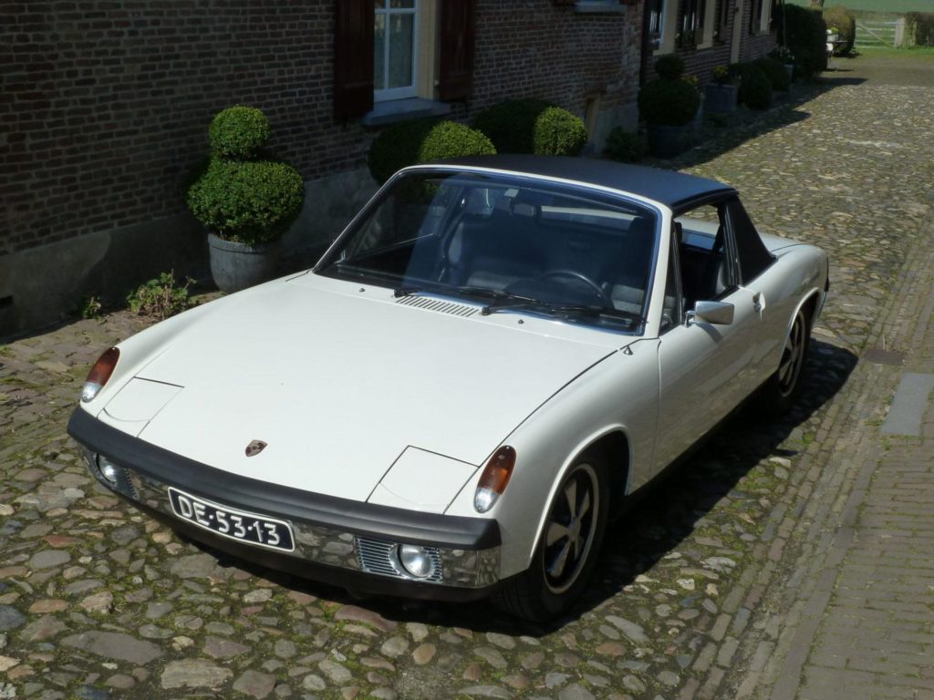 Wat is een echte? Wat met Bugatti’s, Bentleys en Laverda SFC’s gebeurde/gebeurt, dat geldt ook voor Porsche 914 zescilinders. Er zijn replica’s op de markt. Een replica kan iemand heel gelukkig maken. Maar als die replica verkocht wordt als een ‘Echte’, dan gaat het wringen in het kosten/batenplaatje. Raadpleeg dus altijd een kenner voor controle van de motor- bak- en chassisnummers plus de specificaties. De originele blokken hebben nummers die heel krap om de 6400001-6420270 zitten. Dat nummer staat (in tegenstelling tot op de 911´s) boven op het blok bij het huis van de carter ontluchting. De zescilinder motor heeft en dry sump smeersysteem. De olie zit dus niet in het carter, maar in een olietank. Die zit links in het motorcompartiment, tussen binnen en buitenscherm. De beplating van de koeling moest aangepast worden om in de motorruimte van de 914 te passen. Omdat de carburateurs teveel plek innemen zit er geen ´regen afdruip scherm´ in de motorkap. Daardoor is die een ietsepietsie lichter en daarom konden er wat lichter motorkapveren gebruikt worden. Dat is liefdevol denkwerk in de details. De transmissie van de 914/6 is een gemodificeerde 901 versie. Die is best zeldzaam, en niet optimaal. Dit soort bakken schakelde niet zo lekker. Er zijn een paar 914/zessen gemaakt met Sportomatic bakken. De Zessen hadden vijfbouts naven en de meeste werden verkocht met de optinele Fuchs velgen. Ons fotomodel heeft trouwens ook zo’n velg in de reserveband. Dat is stijlvol en scheelt gedoe met verschillende pasbouten. Er kon ook voor Mahle velgen gekozen worden. Het carrosserie van de 914/6 had een aan het schutbord aangelaste motorsteun, Bij de viercilinders zitten er twee motorsteunen aan weerszijden van het blok. De zescilinder heeft een andere stuurkolom, stuurwiel en een ander contactslot.(Op het dashboard in plaats van op de stuurkolom). De voorruitsproeier was voorzien van een elektrisch pompje in plaats van dat hij op de druk van de reserveband werkte. De toerenteller van de zescilinder gaat door tot 8.000 tpm. De snelheidsmeters hoogte aanduiding is 250 km-u. De temperatuurmeter en de tankinhoudsaanduiding zijn gecombineerd. De -6ssen hadden een handgas voorziening voor de pook. Volgens geruchten zou ook de krik van een 914/6 anders zijn.