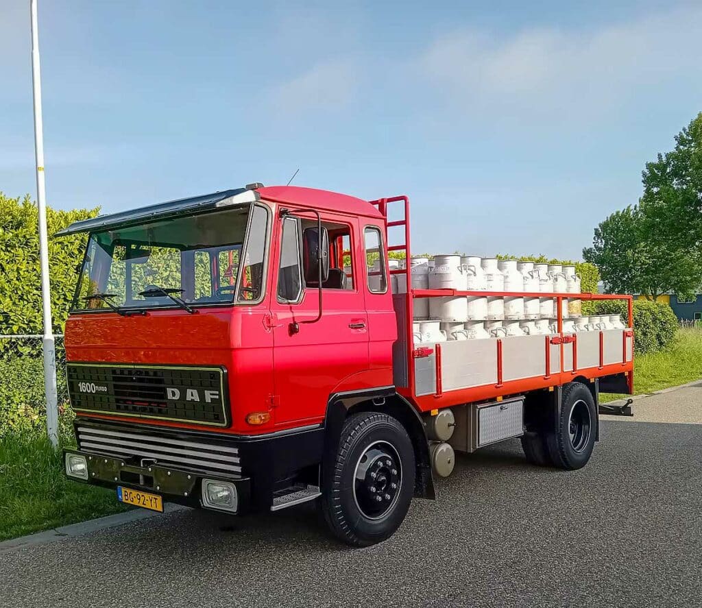 Rode DAF 1600 Turbo vrachtwagen met geladen melkbussen, symbool voor klassiek melktransport
