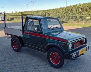 Groen-rode Suzuki SJ 410 pickup uit 1983, in bedrijfskleuren gespoten