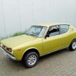 Goudkleurige Datsun 100A uit 1975 in voor drie-kwart linker aanzicht