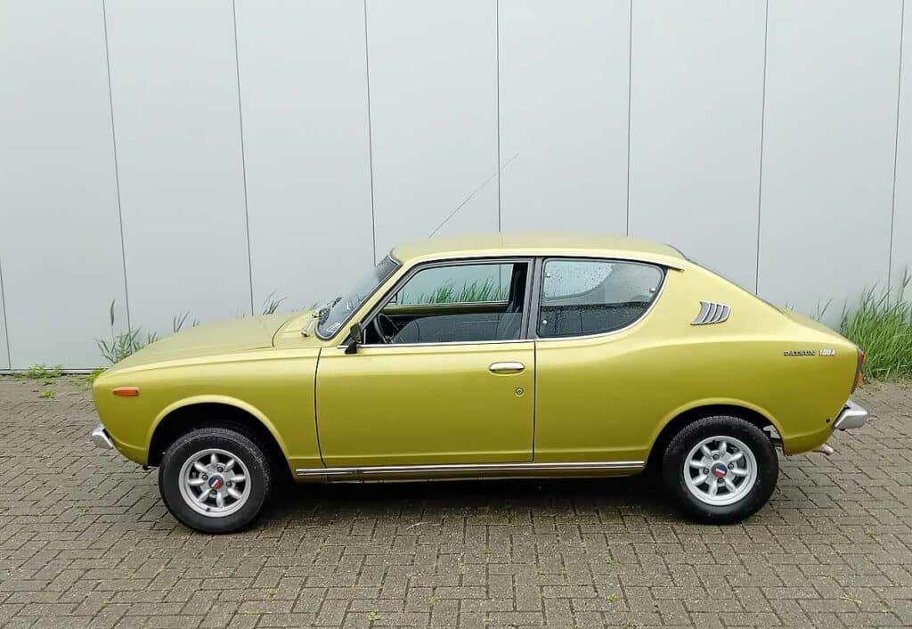Rechter zijaanzicht van een goudkleurige Datsun 100A coupé uit 1975