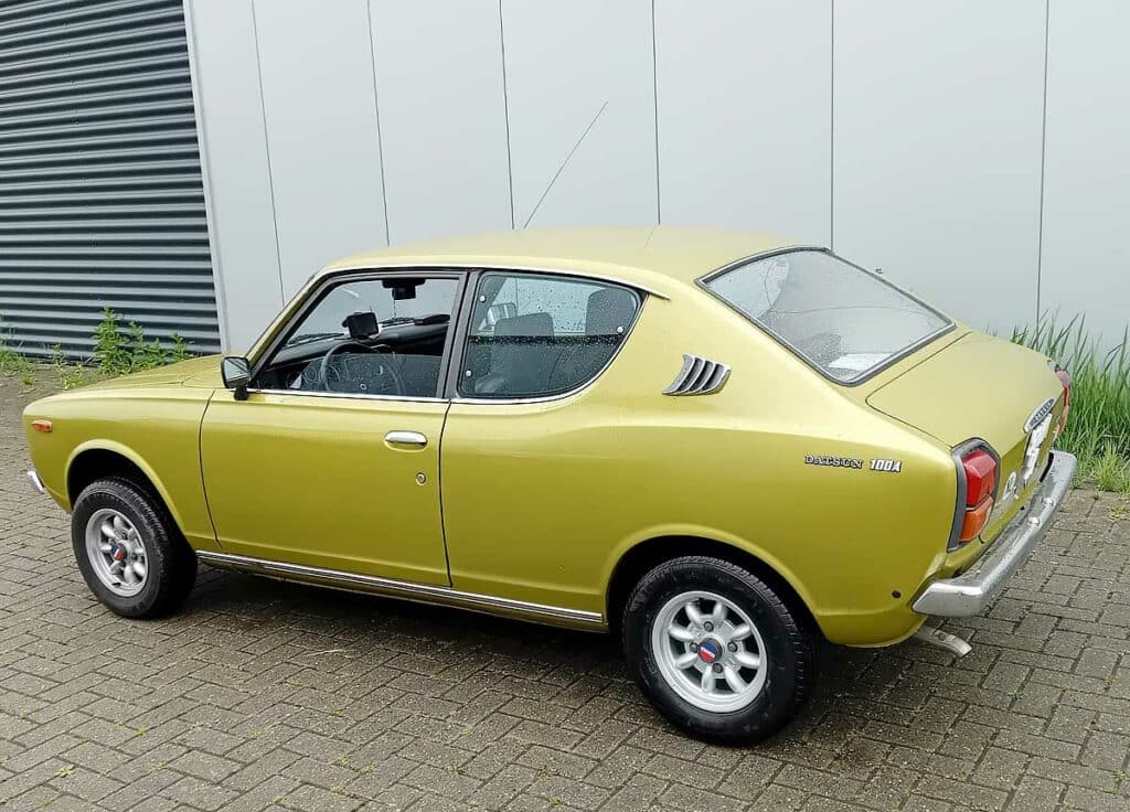 Goudkleurige Datsun 100A uit 1975, achteraanzicht drie-kwart rechts