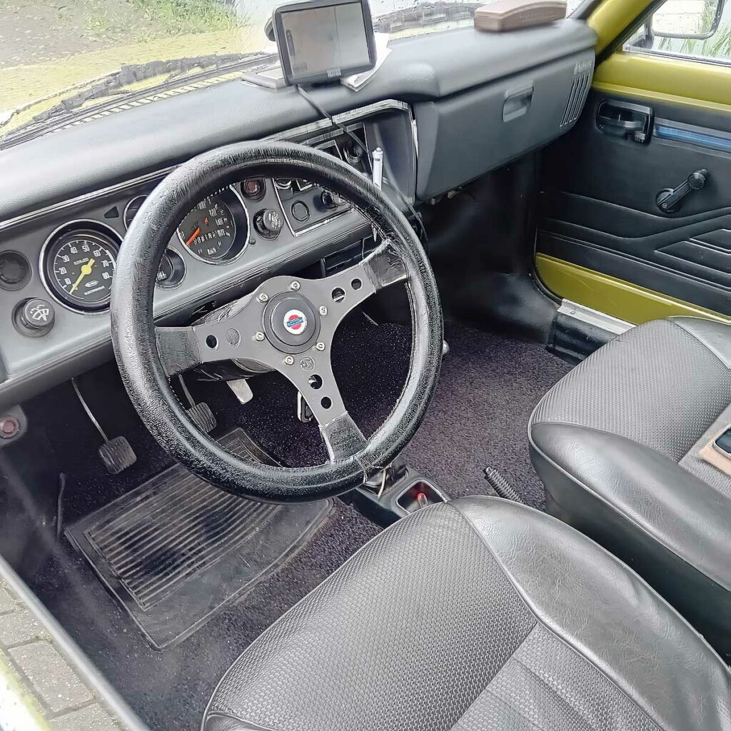 Zwart interieur van een Datsun 100A (1975) met sportstuur en klassiek instrumentarium