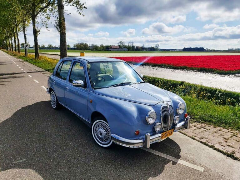 Mitsuoka Viewt in pastelblauw, rijdend langs kleurrijke bollenvelden