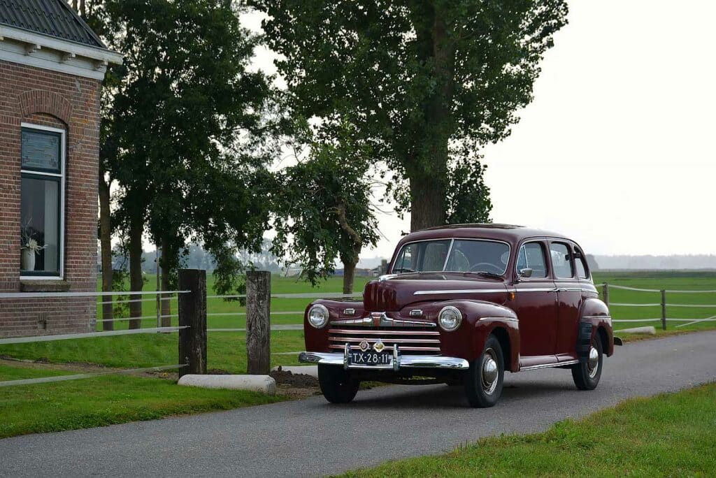 Vooraanzicht van een rijdende Ford Deluxe Fordor Sedan in bordeauxrood